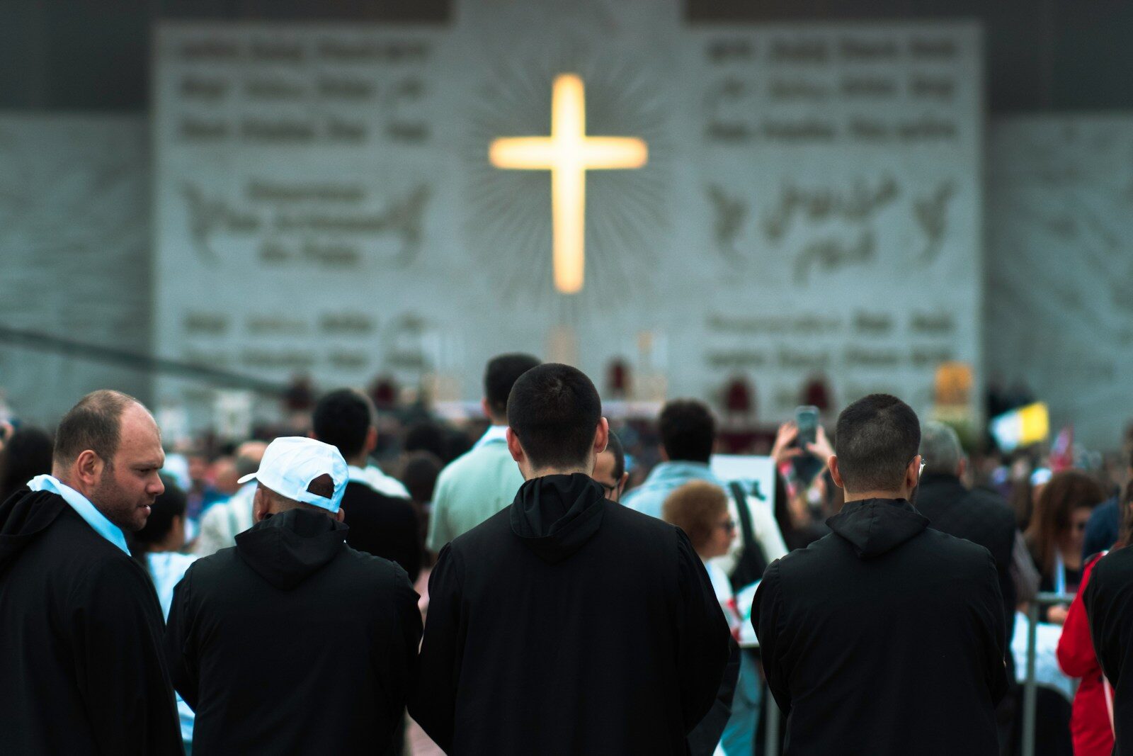 People gathered before a large illuminated cross